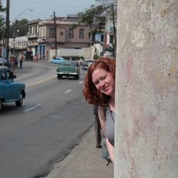 Woman by the street in Cuba with cars