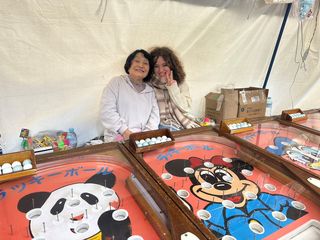 High school student posing with a woman in front of a carnival game in Japan