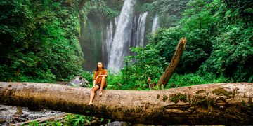monteverde woman on log in front of a waterfall