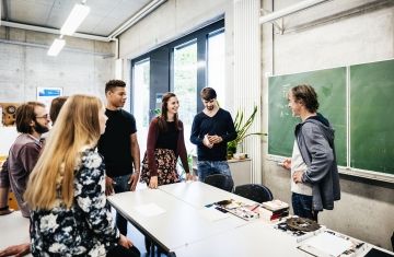 Teacher and students talking around a desk in classroom