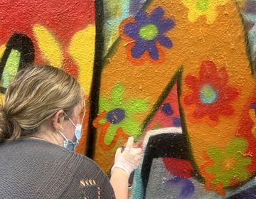 HSSA student Katie Janak sprays flowers on the graffiti mural