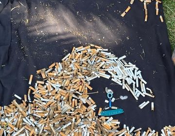 Cigarette art of a surfer riding a wave on top of a black towel. 
