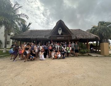 Group of 50 students stands in front of the reception of the beach club