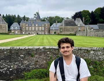 Male teen sitting in front of chateau