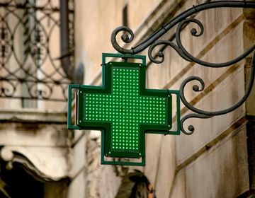 An image of a green cross outside of a building, a symbol used to mark locations as pharmacies in Spain. 