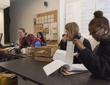 Students and adults reviewing paperwork in cafe