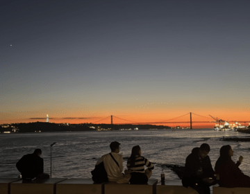 Cais do Sodré sunset, people sitting and talking by the river.