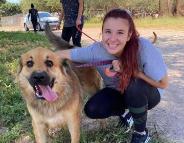 student abroad with dog crouched down smiling