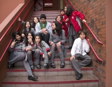 Teach in Chile participant sitting on the steps with Chilean students at school