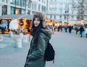 Woman in coat and hat walking down Budapest street