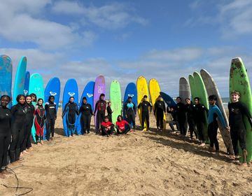 High school participants on beach with their surfboards