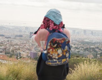 Student taking photo on hill above city while hiking