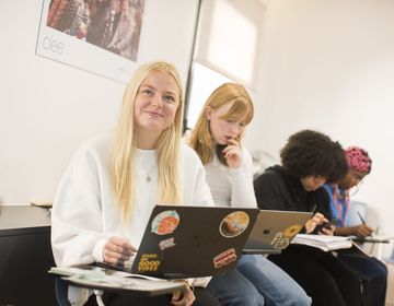 Student with laptop listening and smiling to instructor