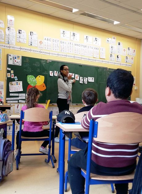 Teacher at front of class teaching students