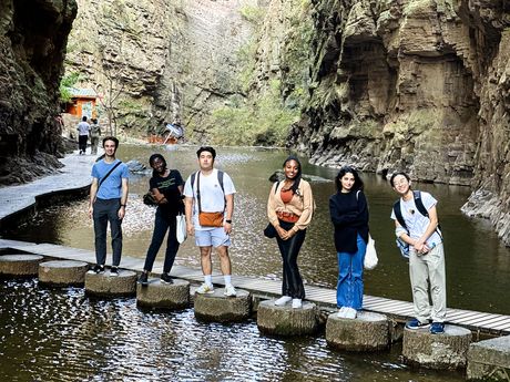 shanghai students standing on rocks in a river