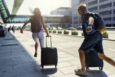 Kids running with their luggage outside an airport