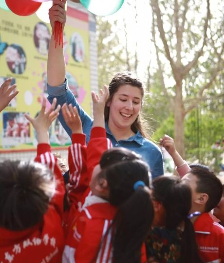 Teacher in China holding balloons in the air above students' heads