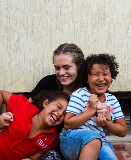 Young woman hugging two laughing kids