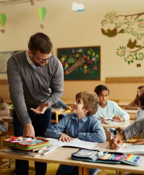 male teacher helping students in classroom