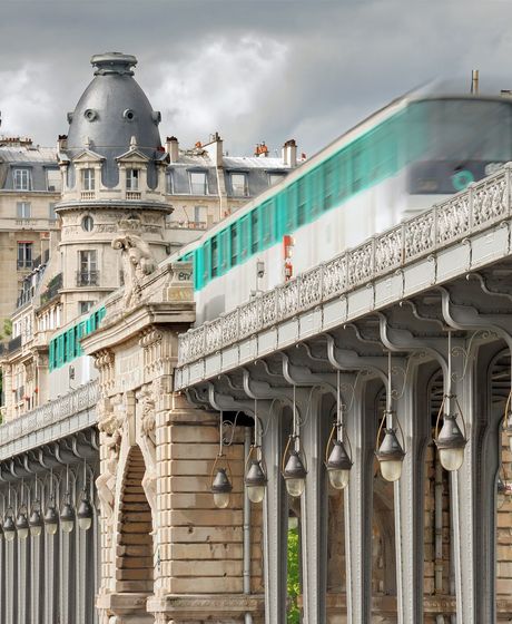 paris metro train going past older architecture