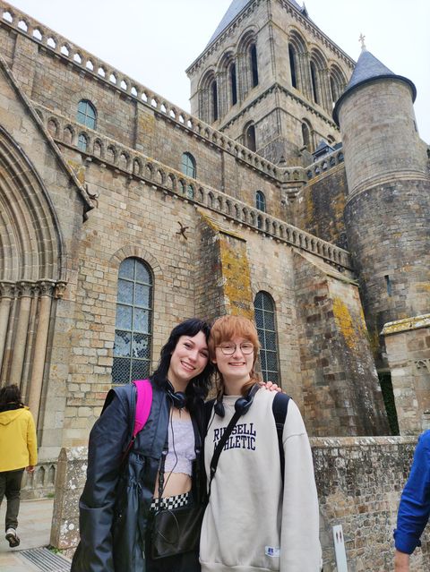 Two high school girls posing in front of an abbey in France