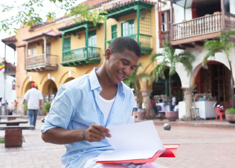 Student on the street in Havana with a journal open before him