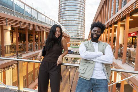 Students leaning against balcony with a tower behind them