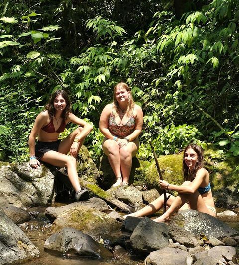 Students on program lounging on rocks in a jungle near the water