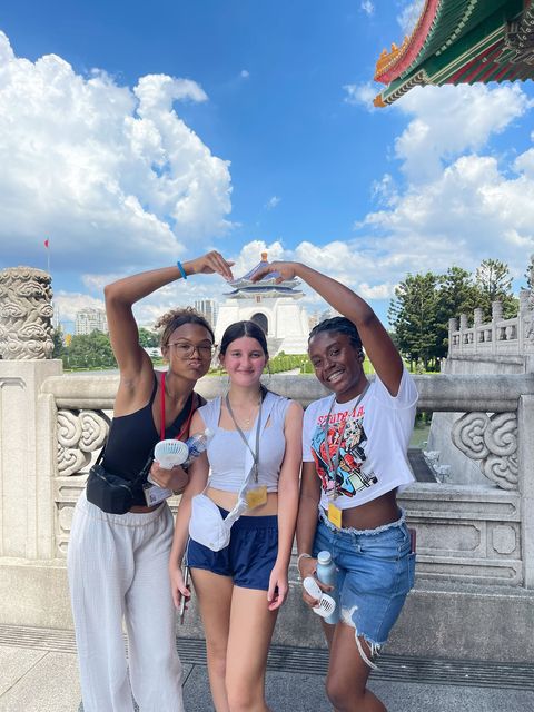 Girls on program in Taipei doing a heart pose in front of a temple