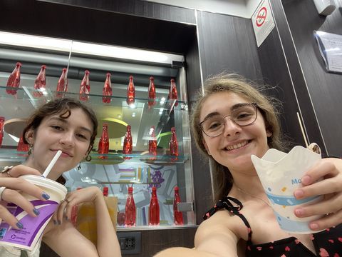 Two girls posing with food and drinks in a store 