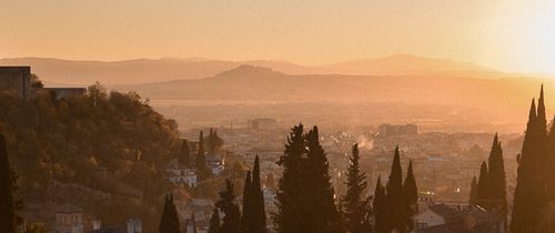 Photo of the sun setting over the city of Granada, Spain.