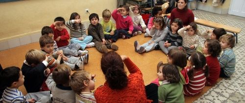 Kids huddled on the floor with their teachers in classroom in Spain