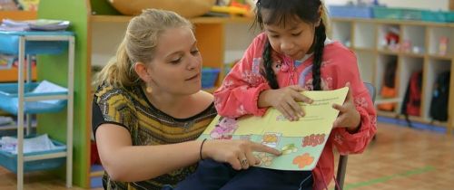 Teacher and student reading a book