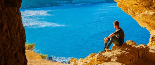 man-overlooking-ocean-from-coastal-cave