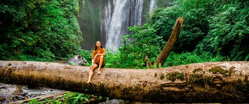 monteverde woman on log in front of a waterfall