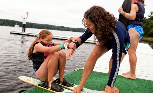 Summer camp counselor and student on water skis