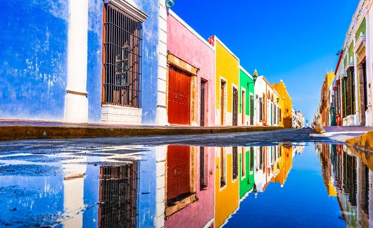 colorful buildings in yucatan mexico reflected in a puddle of water