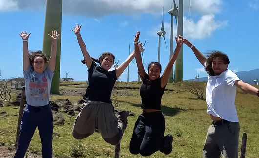 students abroad jumping wind turbines