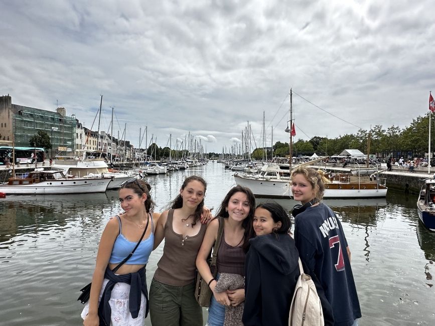 Five girls smiling in front of boats