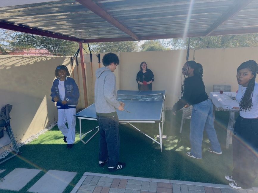 Two global navigators play table tennis with local students.