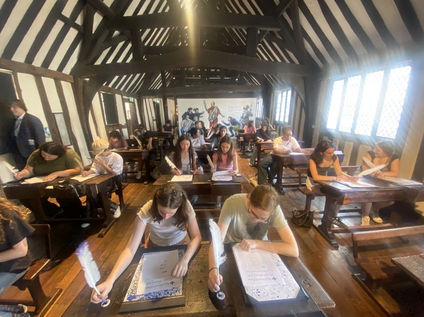 Students in William Shakespeare's school room practicing writing with a feather quill and ink pot. 