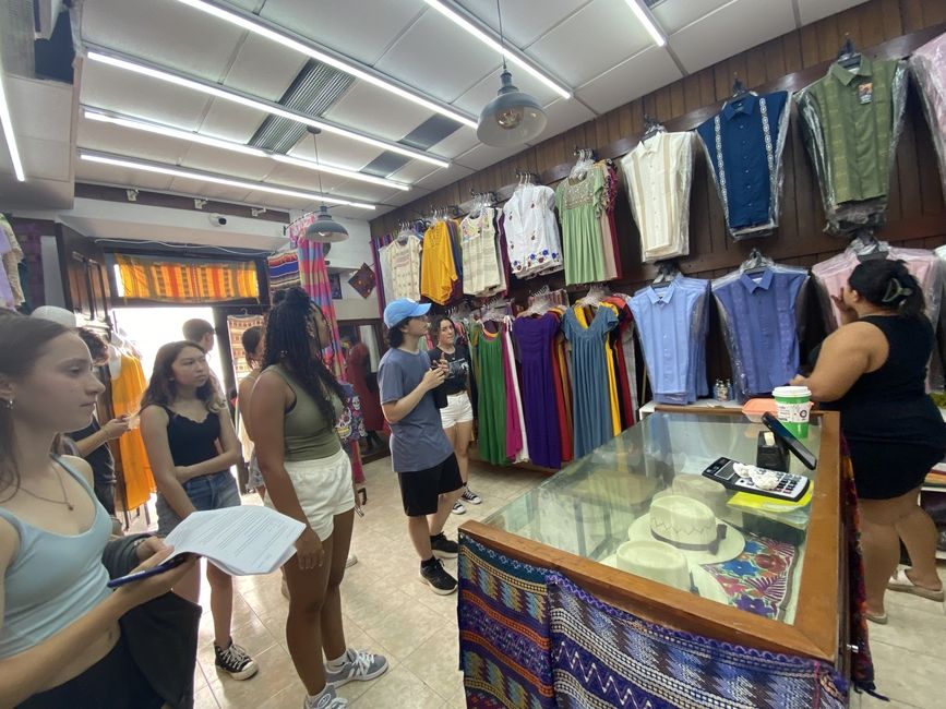 Students enter the store to ask about the typical prices for local traditional clothes.