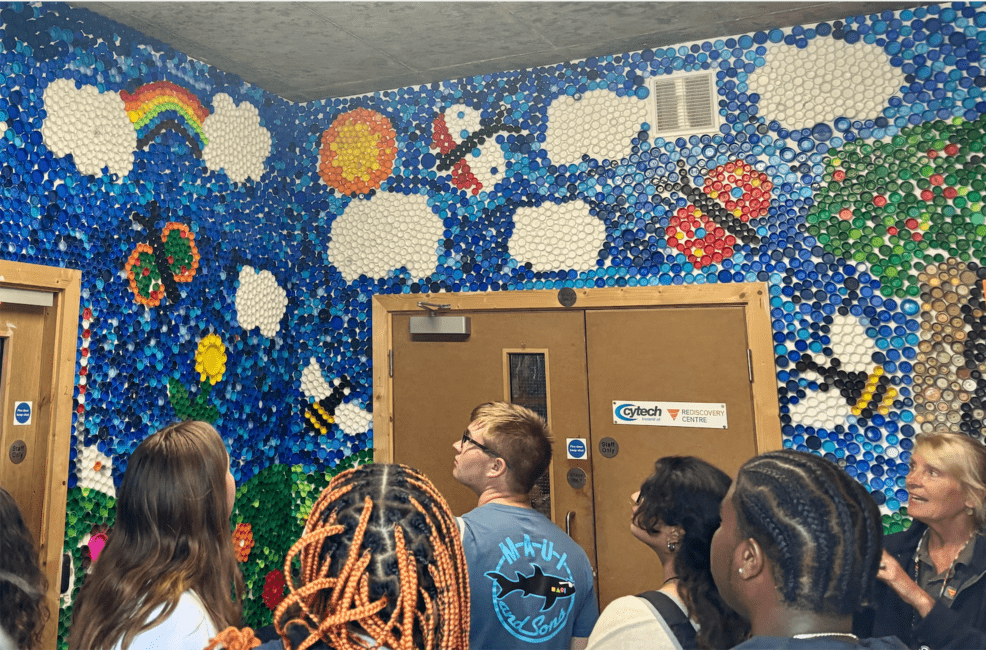 Students observing a mosaic made of bottle caps