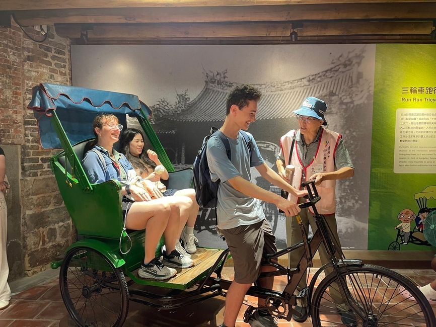Students with their leader and tour guide trying out an old style green rickshaw bicycle 