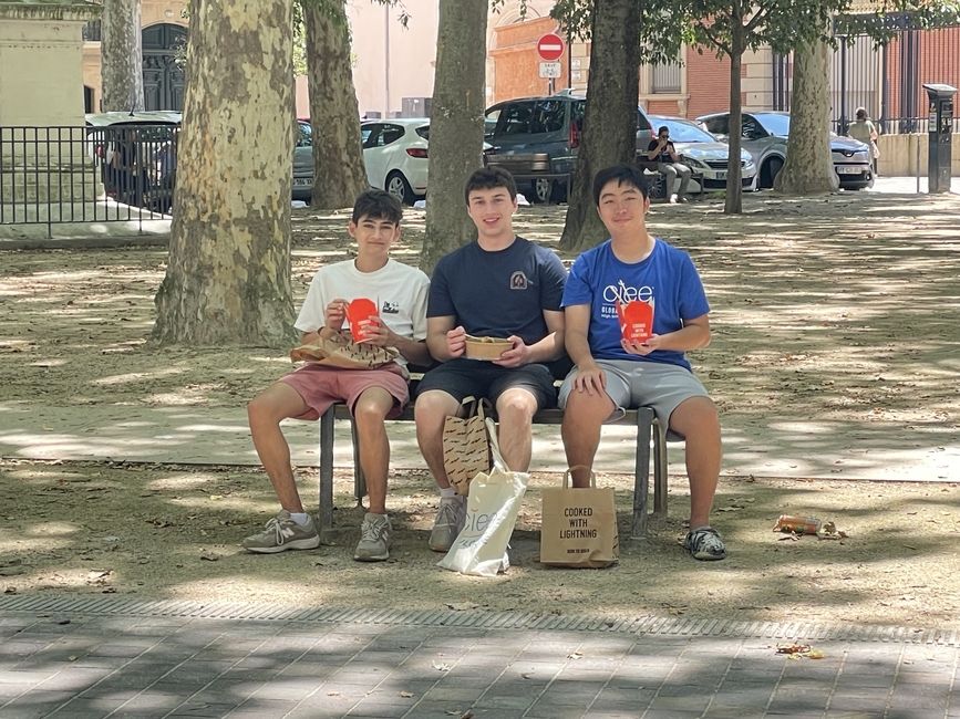 three students sitting on a bench in the park