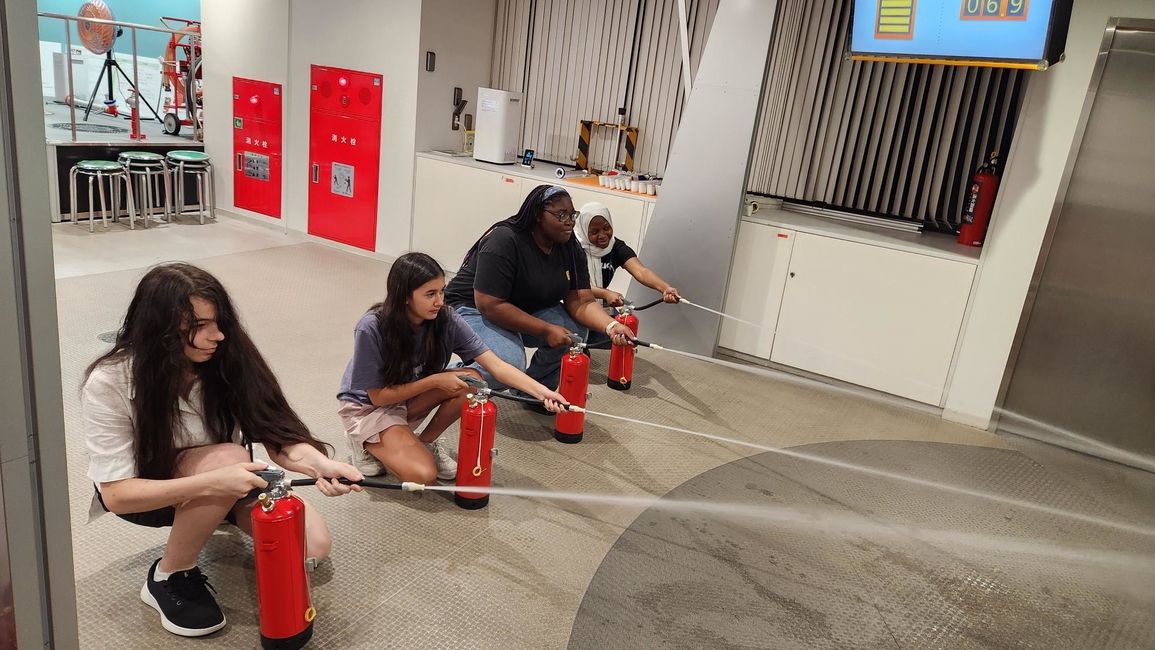 Four CIEE students spray water from practice fire extingishers to learn how to operate one 
