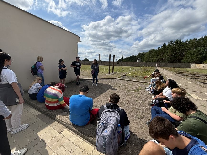 Students listening to tour guide next to the prison within the camp