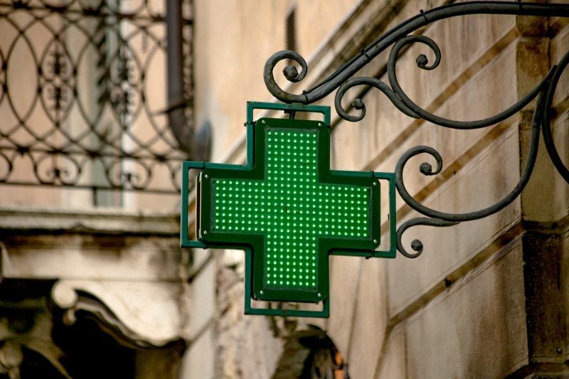 An image of a green cross outside of a building, a symbol used to mark locations as pharmacies in Spain. 