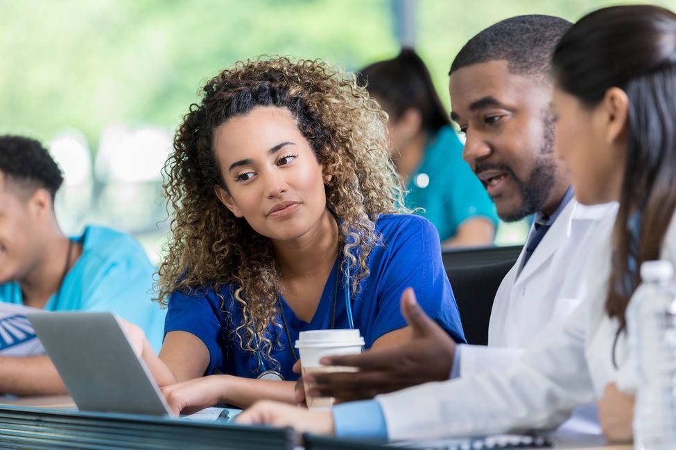 Students sitting in lecture hall looking at laptop