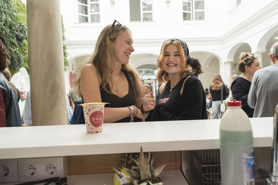 Two girls laughing while leaning against table